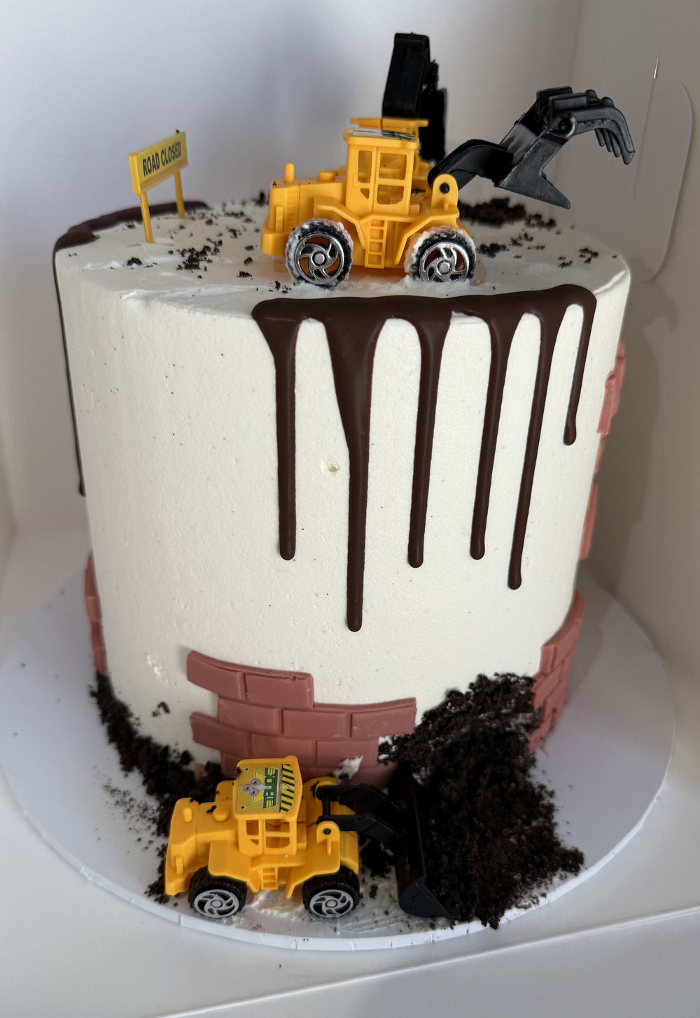 Cake with chocolate drizzle and toy truck on top