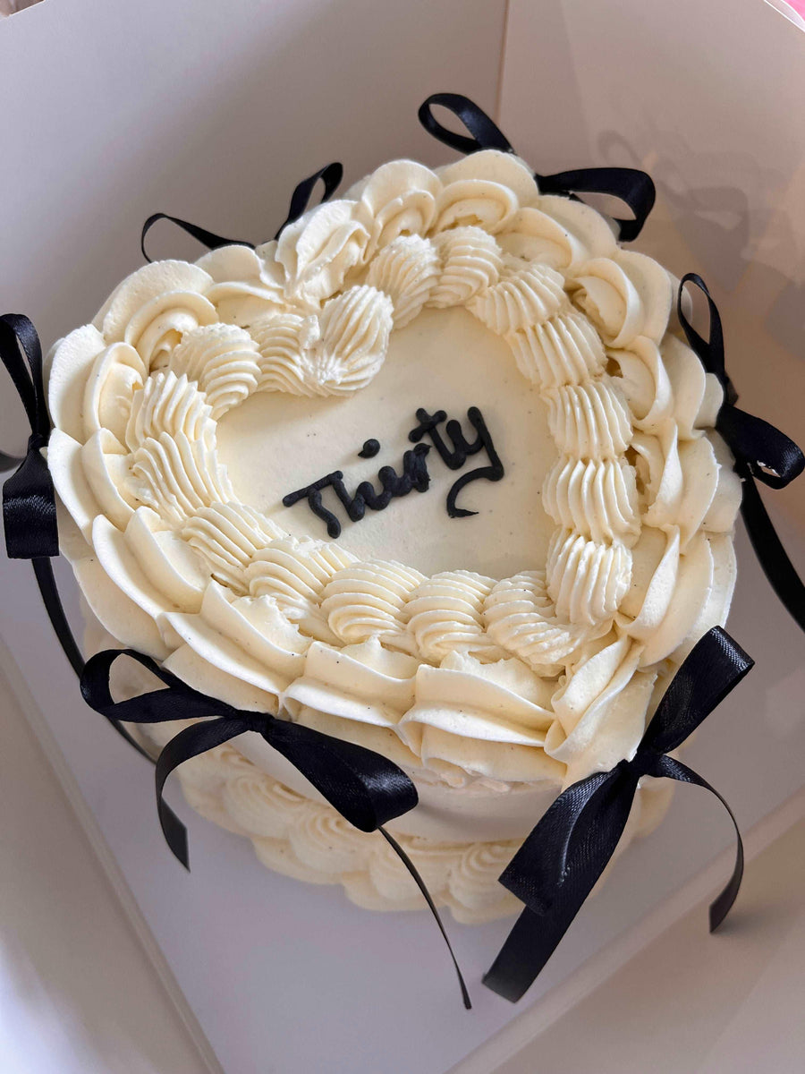 Heart-shaped vintage cake with hand-piped message and elegant bows, perfect for birthdays, anniversaries, and special occasions.