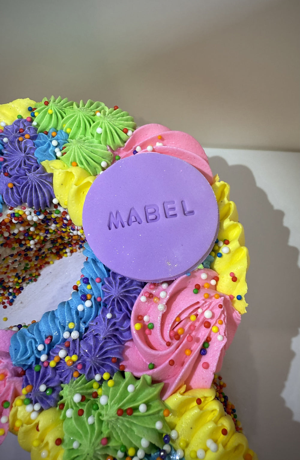 Colorful cake with 'MABEL' on a purple round decoration