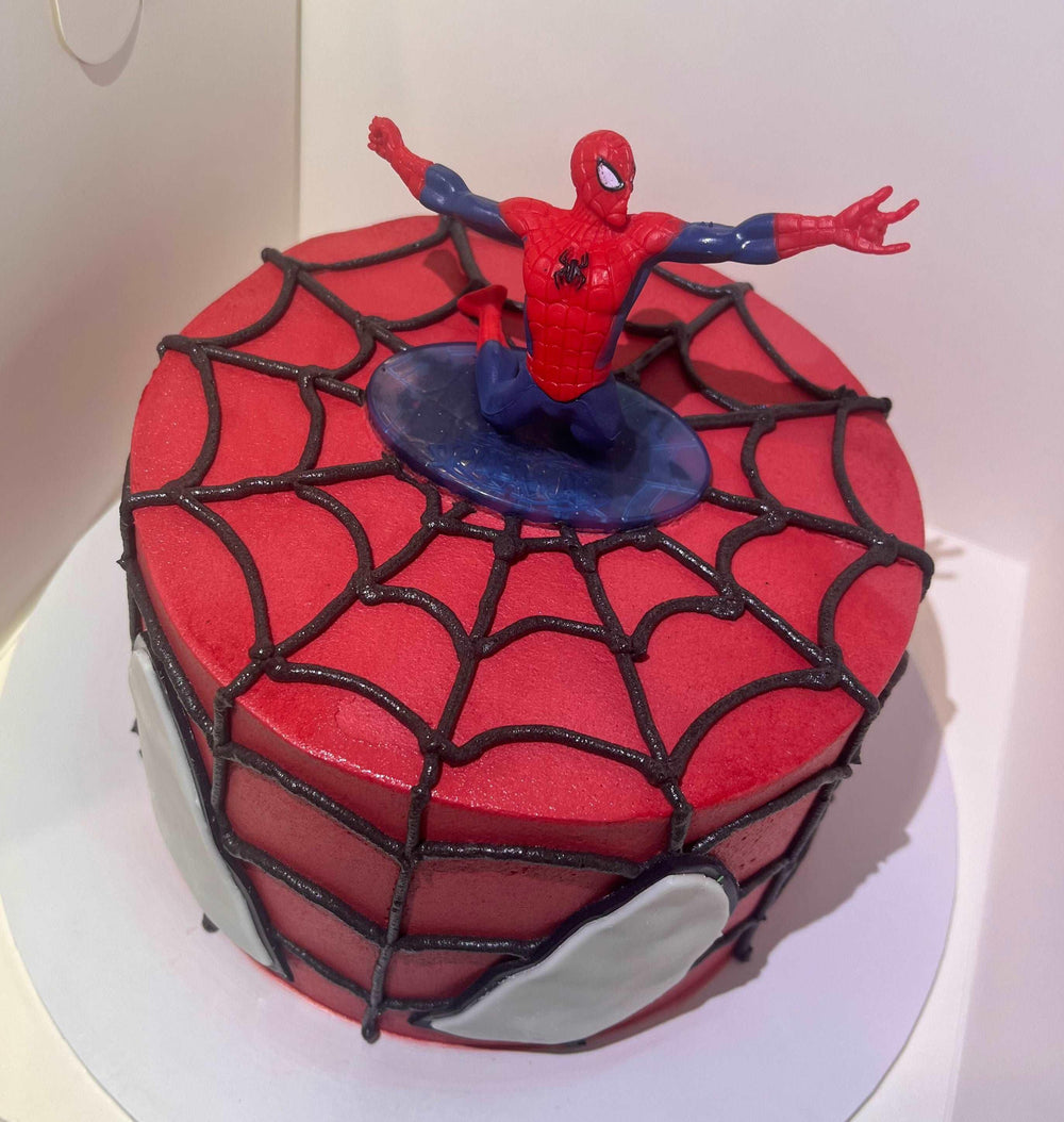 Spiderman Cake, Close-up of Spider-Man figurine on top of a birthday cake, surrounded by web design and bold red and black icing, ideal for kids' superhero parties.
