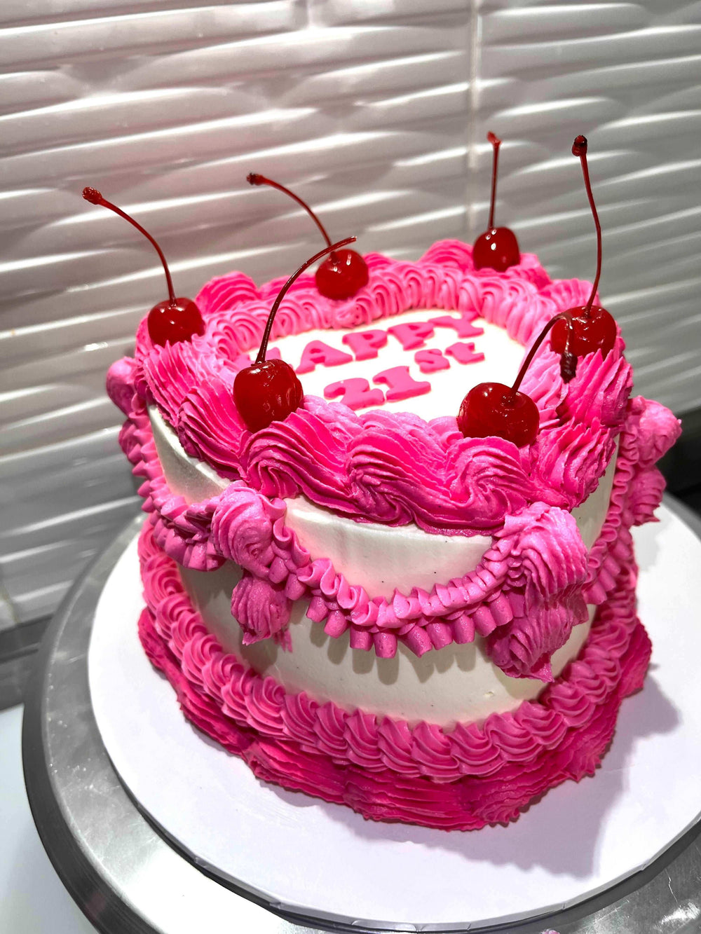 Customizable heart-shaped vintage cake with a fondant message, delicate hand-piping, and cherries on top, featuring customer-chosen colors, perfect for birthdays and special occasions.