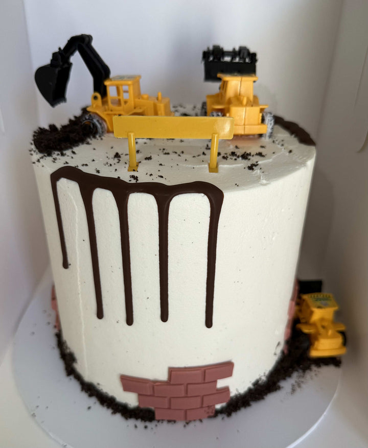 Construction-themed birthday cake with toy bulldozer and truck on top