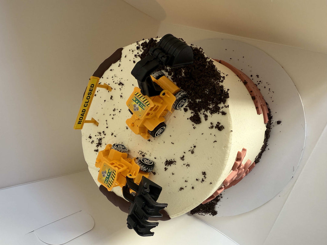 Cake with toy construction vehicles on a white plate