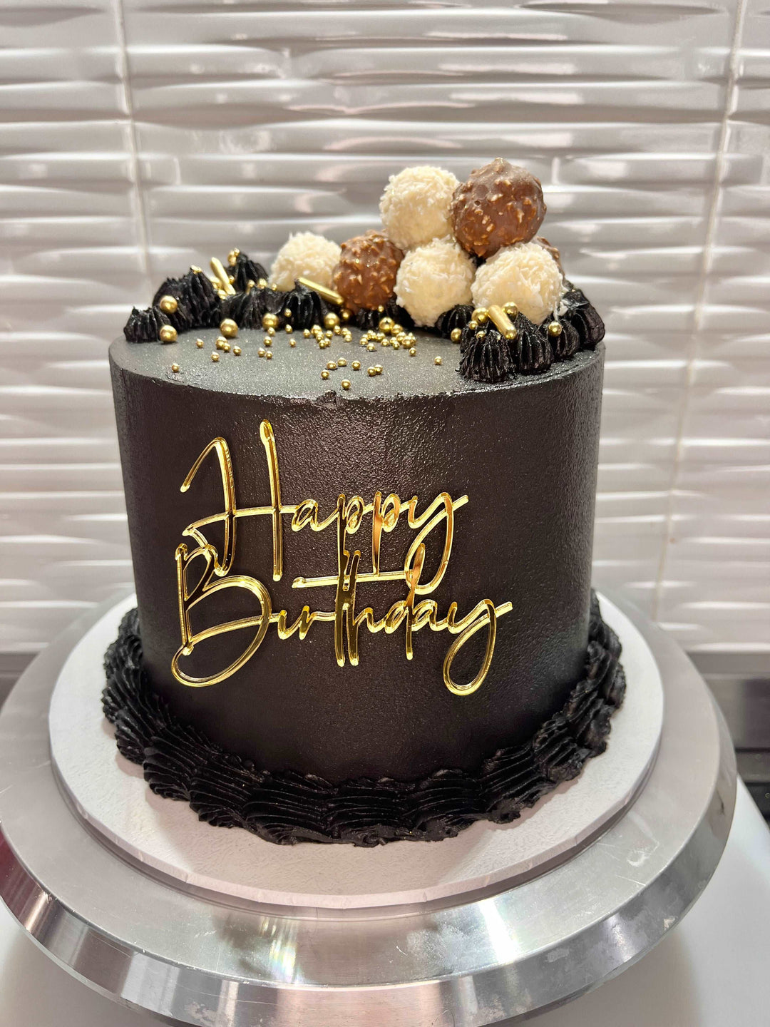 Black and gold happy birthday cake with chocolates