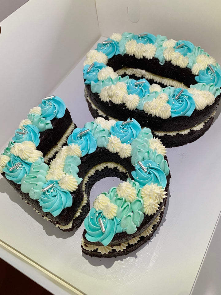 Number 50 cake with blue and white icing on a white surface