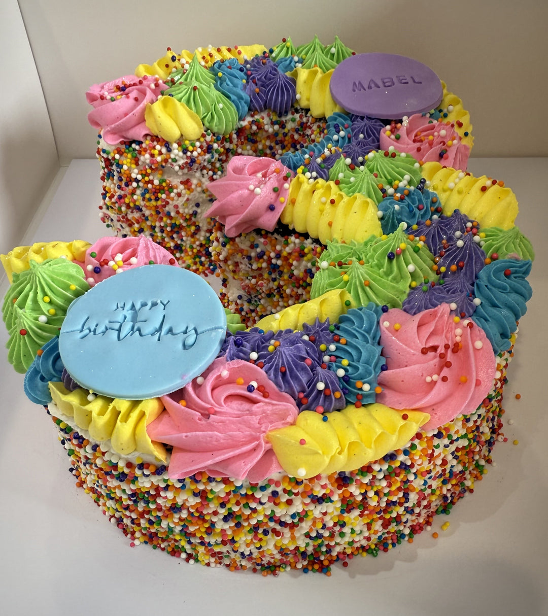 Colorful birthday number cake shaped like the number '3' with sprinkles and icing decorations.