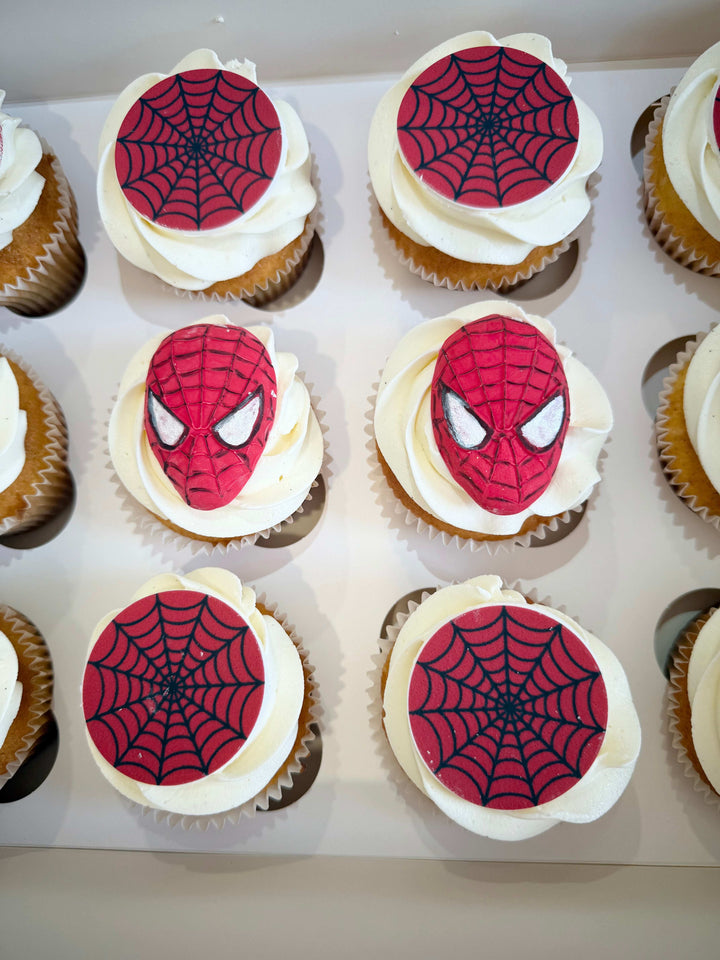 Cupcakes decorated with Spider-Man faces and web patterns on a white tray.